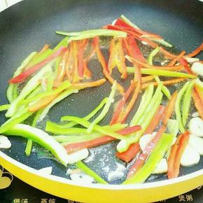 热锅倒入适量植物油烧八成热，放入大蒜爆香，再倒入青红椒翻炒至七成熟。