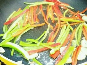 热锅倒入适量植物油烧八成热，放入大蒜爆香，再倒入青红椒翻炒至七成熟。