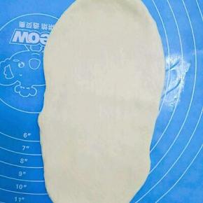 取一个面团擀成椭圆形，从下往上卷起，放入土司盒