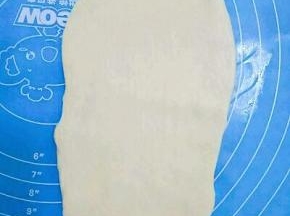 取一个面团擀成椭圆形，从下往上卷起，放入土司盒