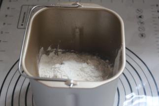 面包机内加入清水和糖粉，上面加入面粉。