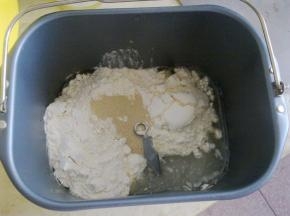 取出面包机内胆，在里入先加入水、色拉油、糖、盐，然后加入全部面粉，最上面放上酵母，把内胆装入面包机内，按下“发面团”功能键。