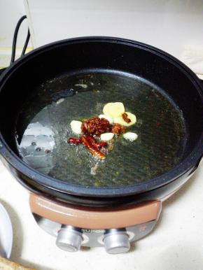 煎烤机内放入两大勺玉米油，烧热后，放入辣椒，花椒，郫县豆瓣酱，姜，蒜，芹菜翻炒出香味