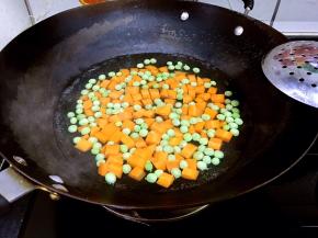 炒锅做水，水开炒烫胡萝卜丁和豌豆。捞出沥干水分。