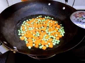 炒锅做水，水开炒烫胡萝卜丁和豌豆。捞出沥干水分。