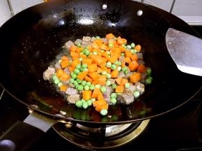 倒入炒烫好的胡萝卜丁和豌豆翻炒均匀。