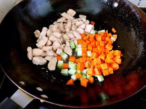 翻炒至鸡丁变色。放入胡萝卜和莴笋丁翻炒。