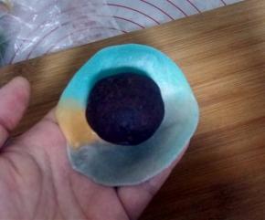 将擀好的面团翻面，放上一个豆沙蛋黄。