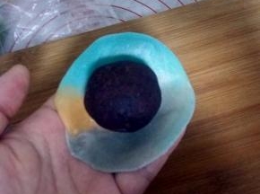 将擀好的面团翻面，放上一个豆沙蛋黄。
