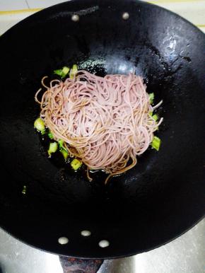 放入沥好的面条，加0.5茶匙盐，转中火，不停的翻炒，以免粘锅