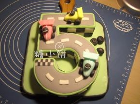 觉得有点单调，又用深灰色翻糖把绿色的底面包了一圈黑边。
又做了几只轮胎摆放在右上的空白处作为点缀，之后插旗子用。
