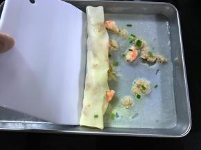 取出后用刮板慢慢将肠粉卷起装盘。