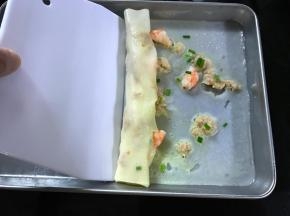 取出后用刮板慢慢将肠粉卷起装盘。