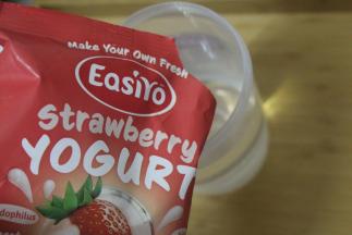 然后慢慢倒入酸奶粉。接着再加入清水至9分满。