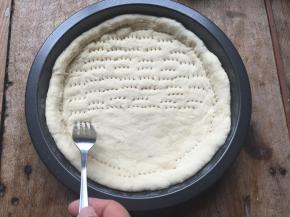 8.用擀面杖将发酵好的面团擀成跟模具差不多大小的形状，放入模具内，让面团完全贴合四周；用叉子在面团上叉一些小孔，避免面团在烤的时候鼓起来；