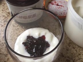 先在杯子里，放入一勺酸奶；再放入一勺果酱；