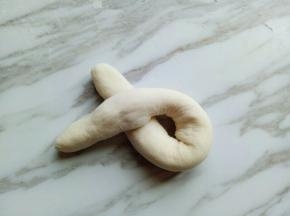 右手的长条压在左手的面团上。