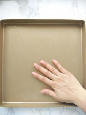 接下来做泡芙面糊。我们先做好准备工作。用手掌在烤盘上涂抹薄薄一层黄油。（不沾烤盘忽略）图中我演示时借用的是不沾烤盘。