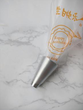 把裱花袋装入花嘴，然后扭转袋子将花嘴前端部分塞入其中。