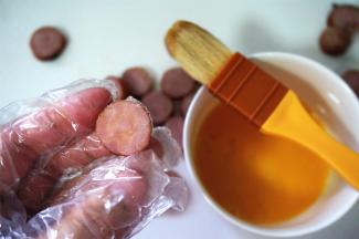 在香肠片的其中一面刷上一层全蛋液。