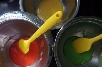 将蛋黄糊平均分成3分，其中两份分别滴入红色素和绿色素，拌均匀。