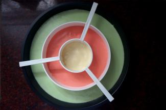 棋格蛋糕模具底部垫上圆形油纸，按照绿红黄的顺序挤入三色蛋糕糊，震荡出大气泡，取掉分隔器。