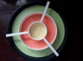 棋格蛋糕模具底部垫上圆形油纸，按照绿红黄的顺序挤入三色蛋糕糊，震荡出大气泡，取掉分隔器。