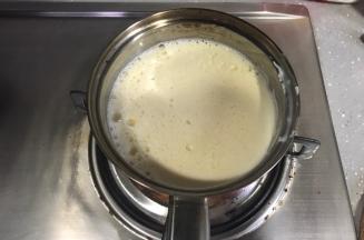 牛奶倒完后，将蛋黄糊倒回奶锅，小火加热。