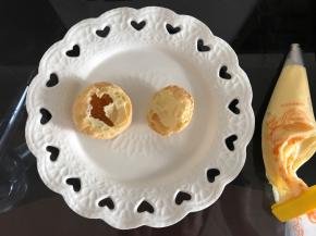 将冷藏好的卡仕达酱装入裱花袋，泡芙从三分之一处切开，可以看到内部有空洞。空洞处挤满卡仕达酱。