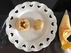 将冷藏好的卡仕达酱装入裱花袋，泡芙从三分之一处切开，可以看到内部有空洞。空洞处挤满卡仕达酱。