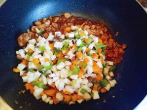 鸡肉炒熟后将焯过水的蔬菜加入，小火煸炒。