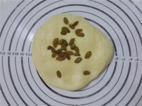 把面团按扁放一半的葡萄干。然后对折起来，再揉成圆形。