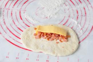 将面团擀成长方形，放入肉肠碎和芝士片。