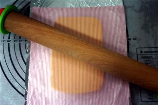 放上一盘锡纸，然后放上面团，隔着油纸，将面团擀成厚1厘米的长方形面片。