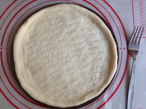 取出面团，排气，滚圆，盖保鲜膜，松驰15分钟。然后擀成圆形，放在9寸披萨盘里，用叉子在面皮上叉出无数小孔，防止烘烤时膨胀