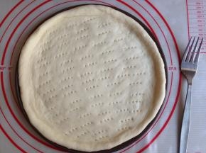 取出面团，排气，滚圆，盖保鲜膜，松驰15分钟。然后擀成圆形，放在9寸披萨盘里，用叉子在面皮上叉出无数小孔，防止烘烤时膨胀