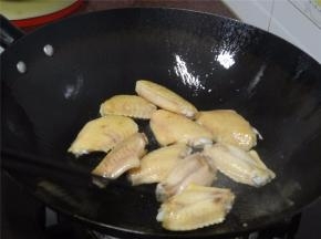 锅里下油，大火烧热后加入鸡翅，煎香。加入几片姜片到鸡翅上。