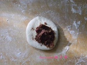 取一小面团压扁，擀圆,放上提前做好的红豆馅；