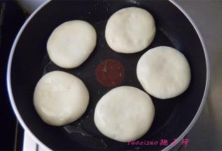 不粘锅里倒入食用油，放入醒发好的红豆饼，小火烙至一面上色后再翻面；