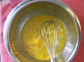 将蛋液盆隔水加热（水温热即可），用手动打蛋器将蛋液、砂糖搅拌均匀，待砂糖基本溶化后，将打蛋盆离开热水；