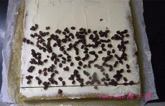 将油纸铺垫在蛋糕的下面，用抹刀将淡奶油抹平，并撒上蜜蜜红豆；