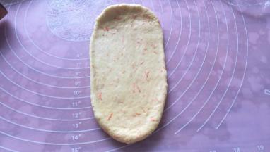 取一个面团擀成椭圆形，拍去两侧气泡。