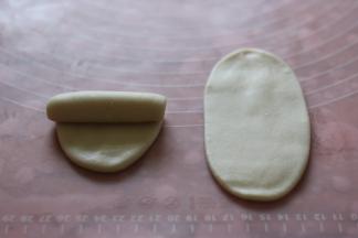 用面杖擀成椭圆形翻面，从上往下卷起。