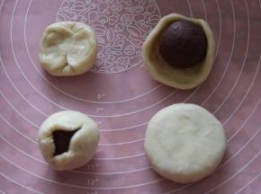 取一个面团，两头对折，用手捏成圆形如图，包入馅料，用虎口捏紧收口。按扁即成月饼。