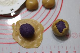 取一个饼皮按扁包入馅料，用虎口慢慢收口，滚圆。