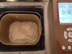 在面粉顶端加入酵母​，将面包桶放入面包机内，选择和面10分钟