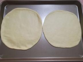 4.将面团拿出来排气，平均分成两份，滚圆，盖上保险木松弛15分钟，用擀面杖将面团擀成两个八寸的圆形。用手调整一下，圆形外圈比中间厚一些。
