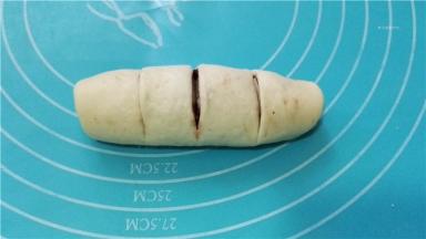 由上至下卷起，底边捏紧成柱形，在面团上切三刀，但不要完全切开，使面团变成四份。