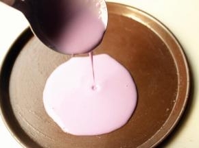 选择不沾的披萨盘，刷一点点油，舀一勺面糊，从中间注入盘子，晃动盘子使面糊铺满盘子。