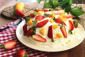 取芒果粒，剩余草莓切两半或者切四半，把芒果粒和草莓装饰在奶油表面。